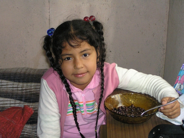 terwijl haar dochtertje frijoles eet (bruine bonen)