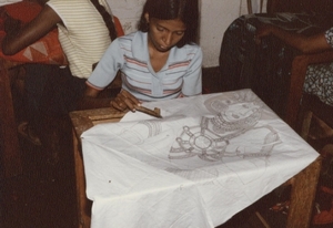 Een meisje van het batik-atelier bedekt figuren met bijenwas