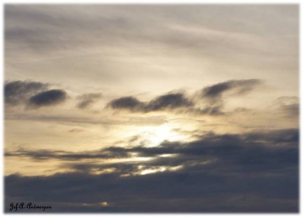 Zon zakt bij valavond achter de wolken. Kattendijkdok Oostkaai