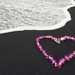 een-roze-hartje-van-bloemen-op-het-strand-hd-hartjes-wallpaper