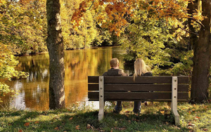 foto-van-twee-mensen-op-een-bankje-bij-het-water-in-de-herfst