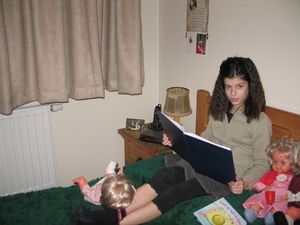 06) Sarah met boek, naast poppen op 't bed