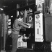 Jongen haalt iets uit een snoepautomaat.