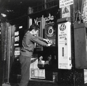 Jongen haalt iets uit een snoepautomaat.