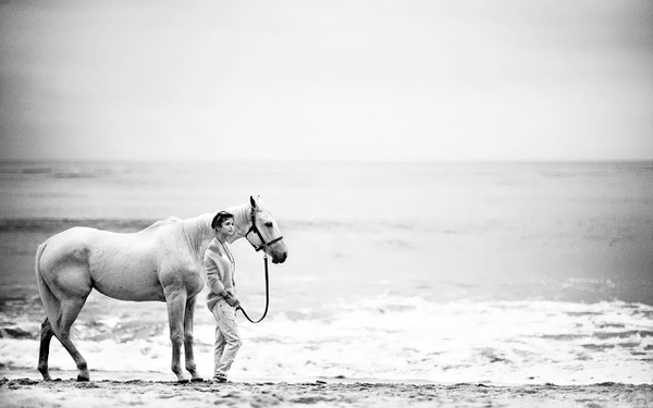 zwart-wit-foto-van-een-vrouw-met-een-paard-op-het-strand