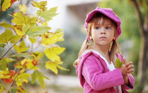 foto-van-een-kind-met-roze-kleding-in-de-herfst-met-herfstbladere