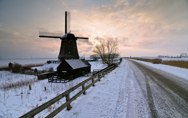 mooi-hollands-winterlandschap-met-een-molen-langs-een-weg-en-over