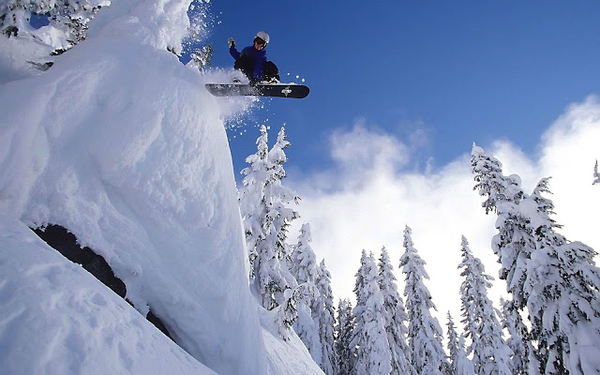foto-van-een-snowboarder-die-van-een-besneeuwde-helling-afspringt