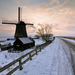 mooi-hollands-winterlandschap-met-een-molen-langs-een-weg-en-over