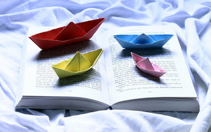 achtergrond-met-gekleurde-papieren-bootjes-en-een-boek